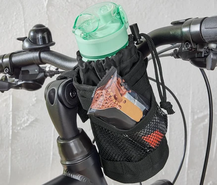 Na riadidlách bicykla je pripevnená taška na drobné občerstvenie na bicykel, v ktorej je fľaša na vodu a tyčinka.
