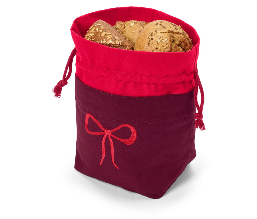 Viaczrnný chlieb v červeno-bordovom látkovom vrecku so sťahovacou šnúrkou a výšivkou mašle.
