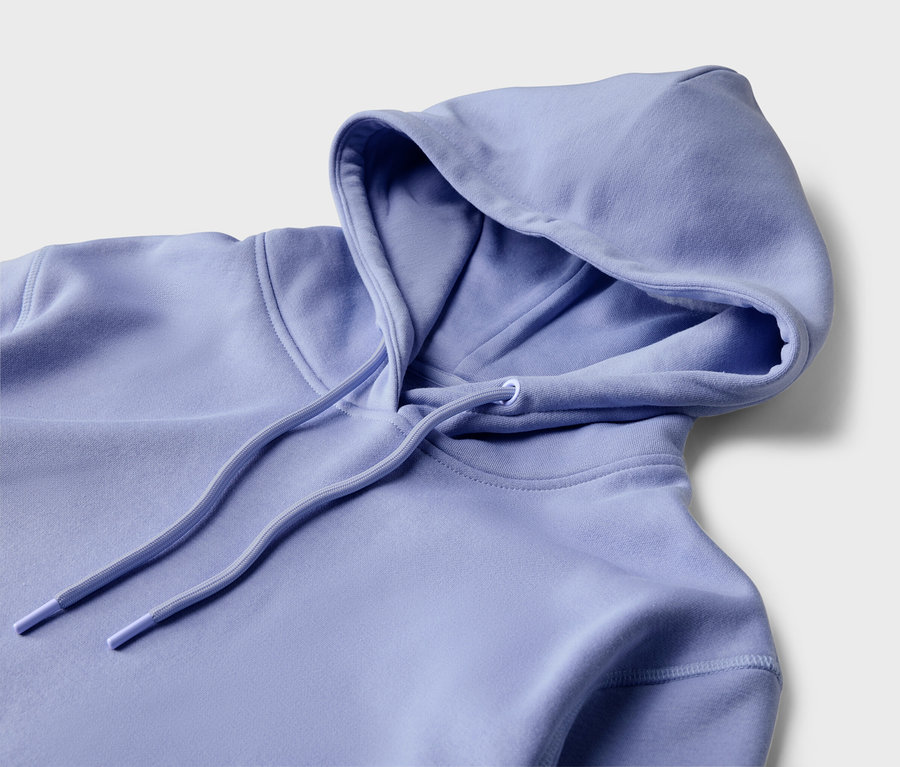 Detail svetlofialovej mikiny s kapucňou a sťahovacou šnúrkou na svetlom pozadí.