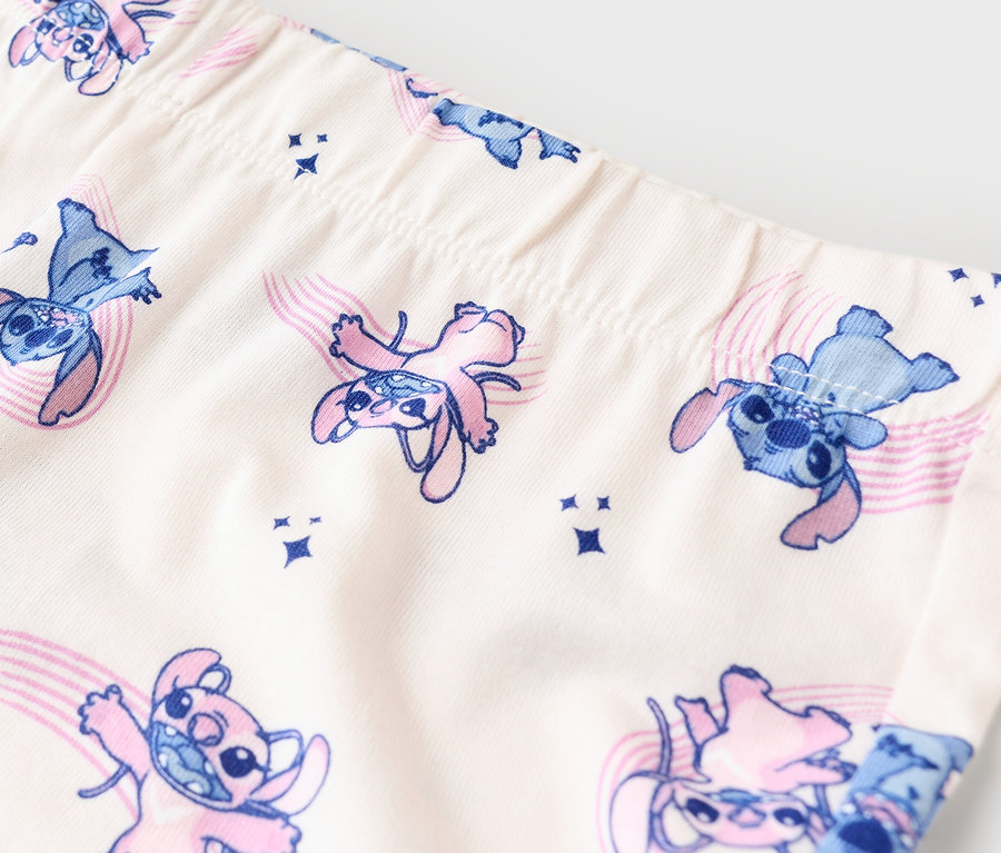 Detailný záber na legíny s modrým a ružovým vzorom Stitch na béžovej látke.