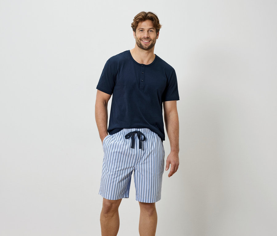 Muž v modrom tričku a pruhovaných šortkách.