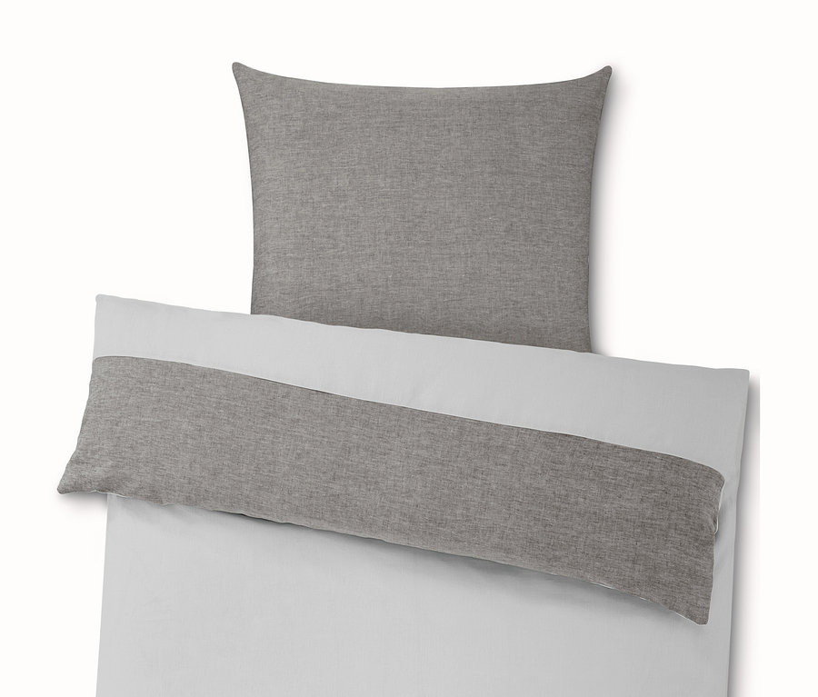 Biela posteľná bielizeň so sivým vankúšom a prikrývkou.