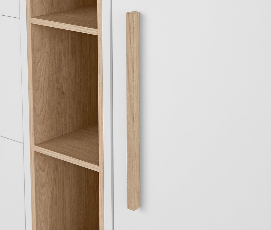 Detail bielej komody »Eklund« so zásuvkami a s dvierkami, s drevenou rúčkou a otvorenými policami.