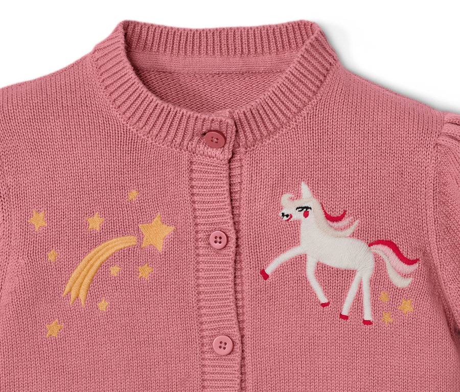 Detail detského svetríka s jednorožcom a hviezdami.