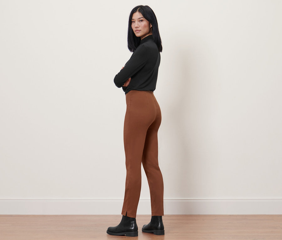 Žena pózuje v koňakových elastických nohaviciach.