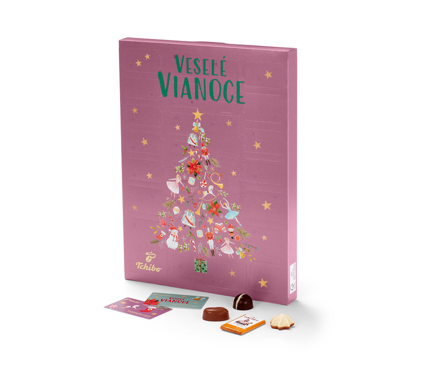 Ružový adventný kalendár Tchibo s vianočným stromčekom a nápisom Veselé Vianoce, vedľa ležia čokolády.