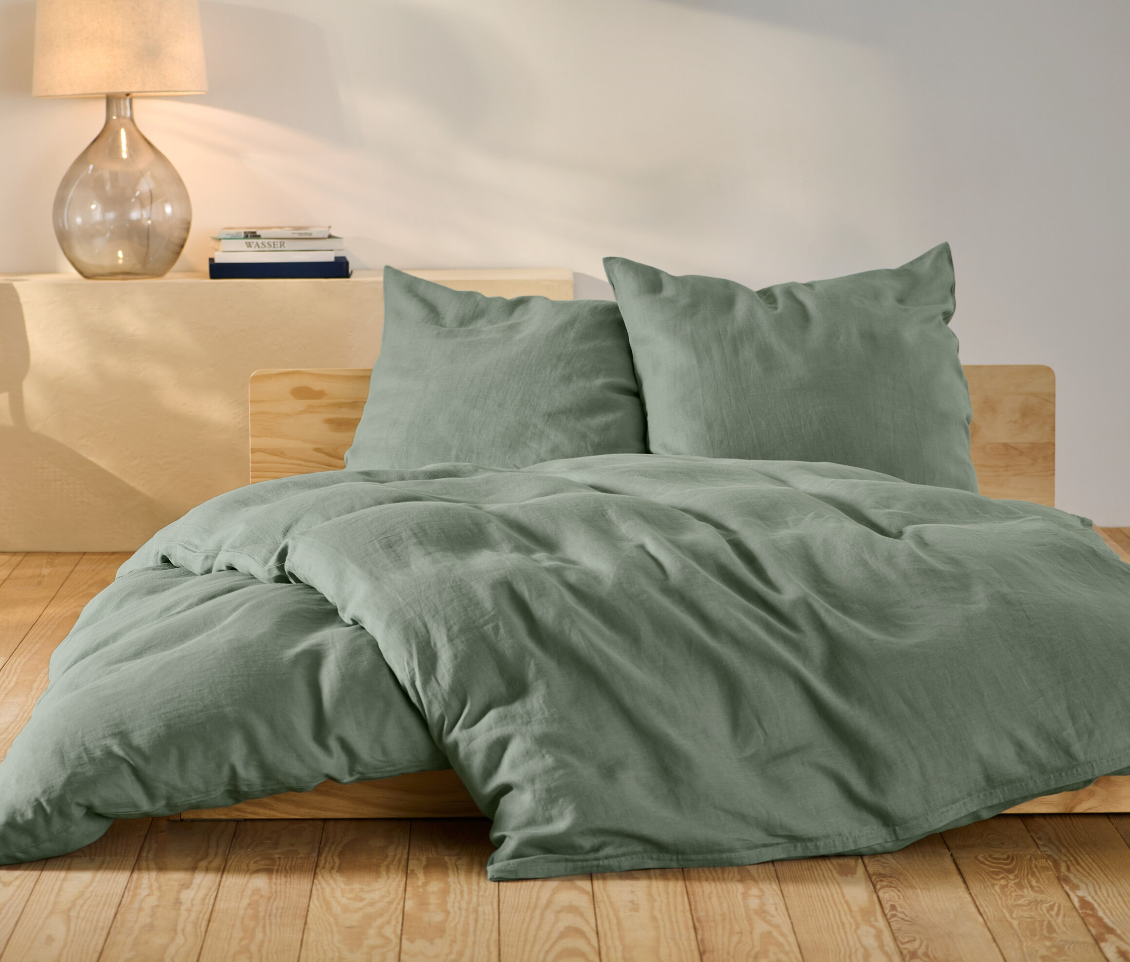 Zelená ľanová posteľná bielizeň štandardnej a nadmernej veľkosti na posteli.