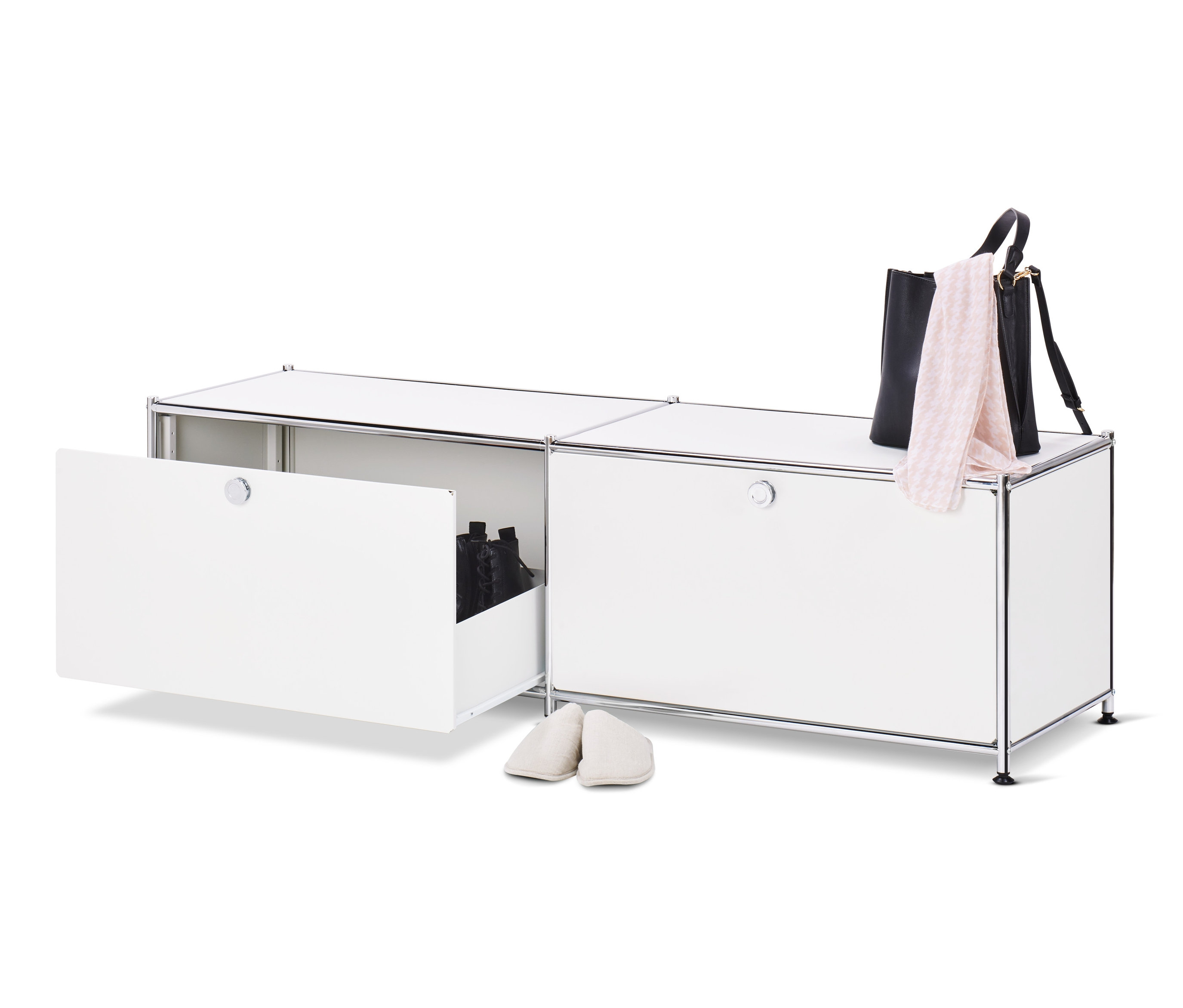 Otvorená biela kovová nízka skrinka »CN3« so zásuvkami a topánkami vnútri, vedľa nej stojí pár krémových papúč, na hornej strane skrinky leží čierna kabelka a ružový šál.