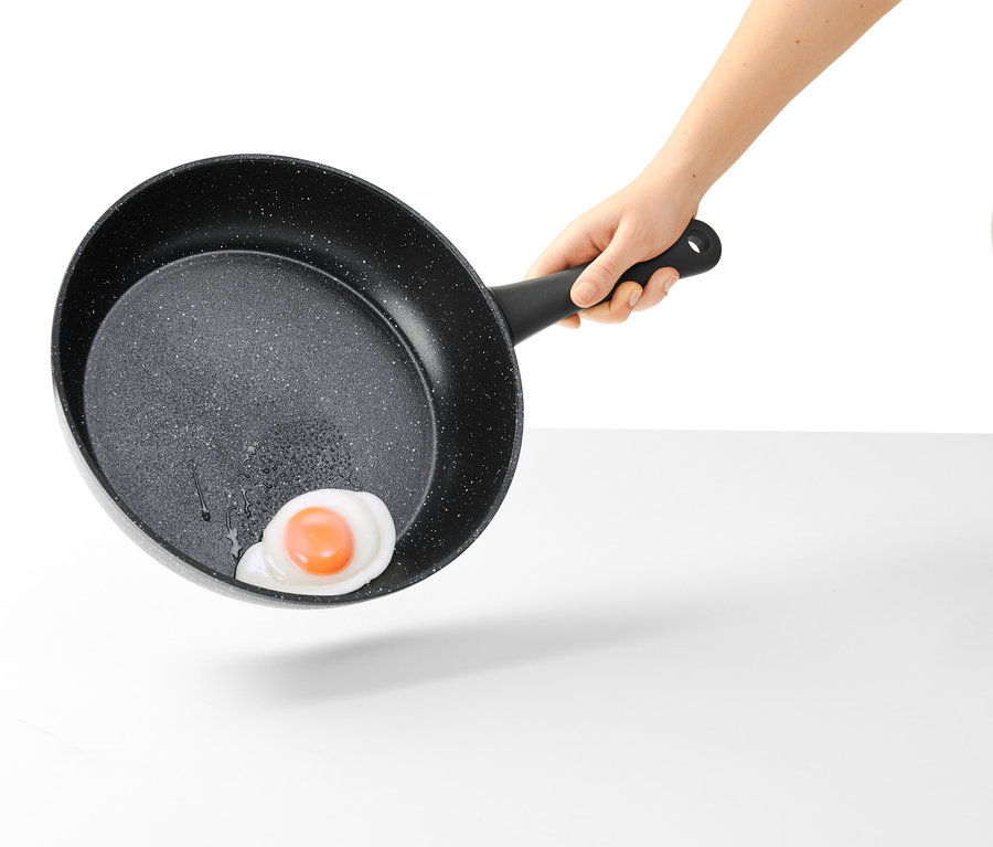 Ruka drží 28 cm profi panvicu vo vzhľade kameňa s praženým vajcom.