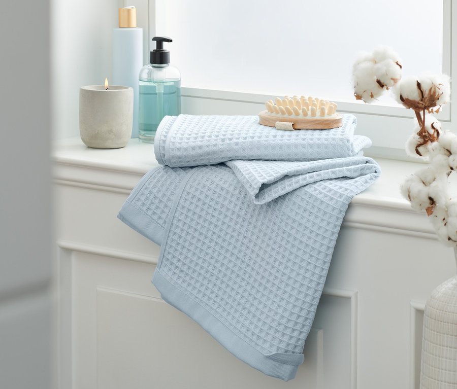 Na parapete ležia dva modré uteráky prémiovej kvality z piké s vafľovou štruktúrou.