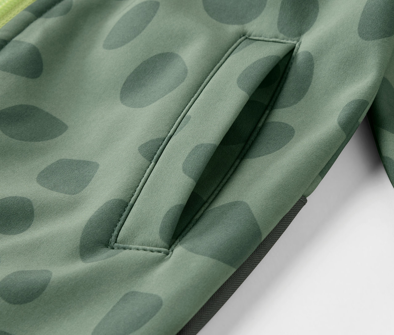 Detail detskej softshellovej kombinézy so vzorom a vreckom.