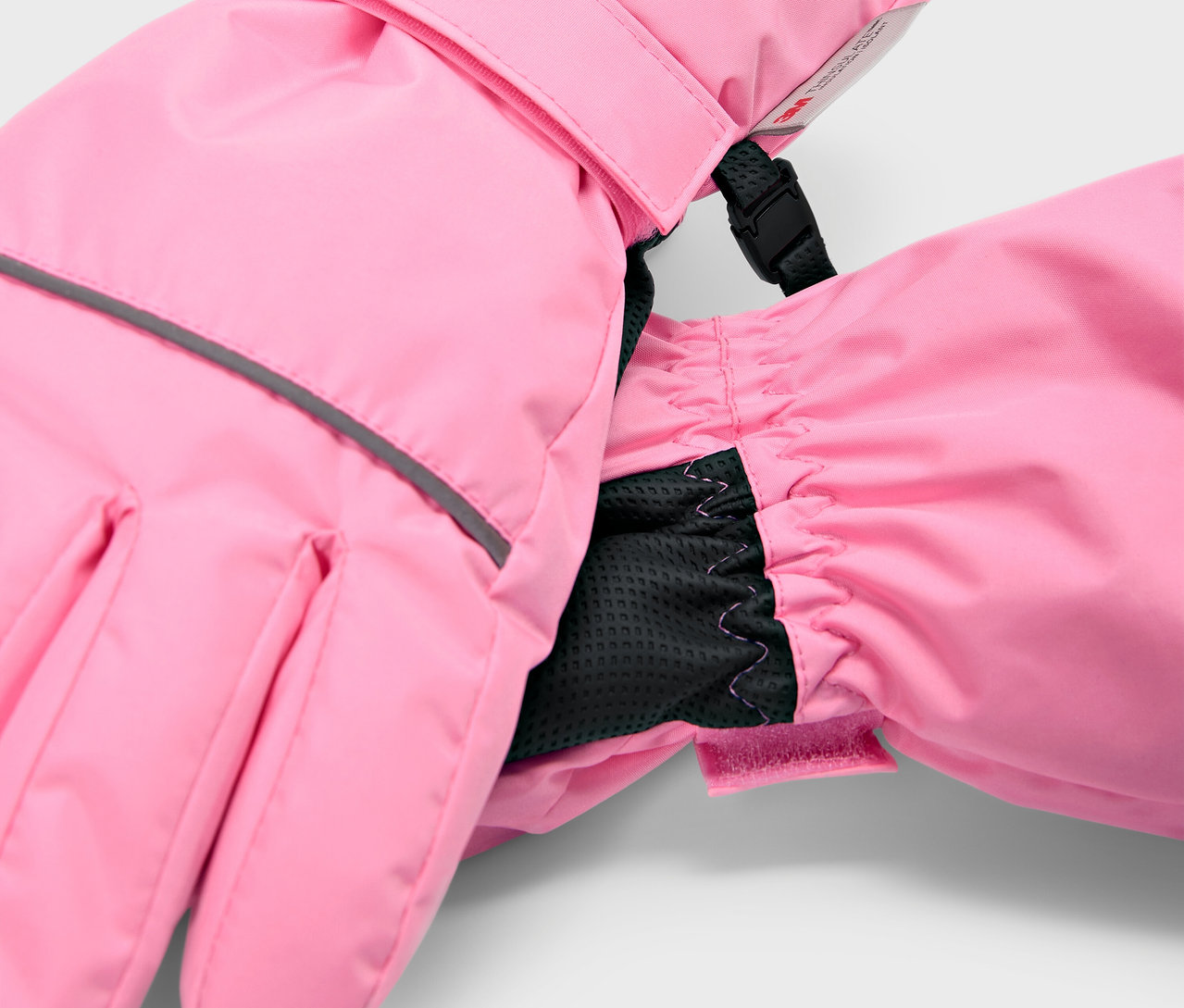 Detail ružových detských lyžiarskych rukavíc s čiernou vnútornou manžetou.