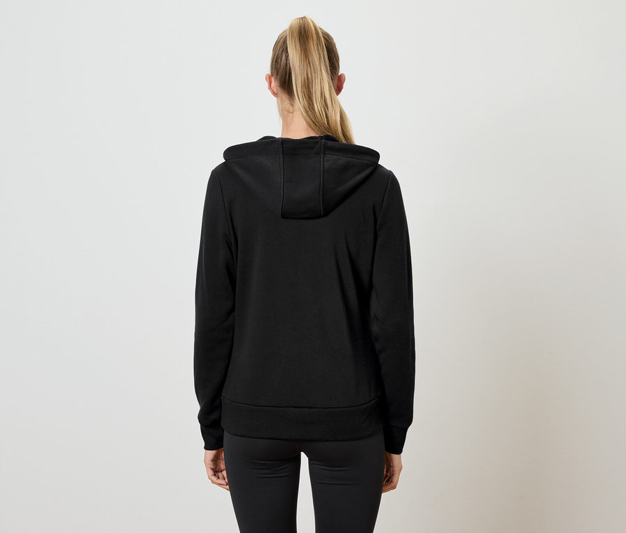 Pohľad zozadu na ženu s blond vlasmi zviazanými do chvosta, oblečenú v čiernej mikine s kapucňou a čiernych nohaviciach.