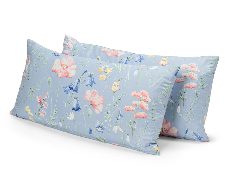 Dva vankúše s kvetinovým vzorom na modrom pozadí ležia jeden na druhom.