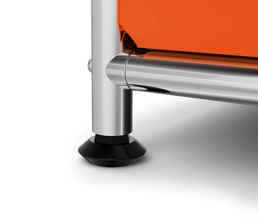 Detail oranžovej skrinky s chrómovanou nohou a čiernou pätkou.