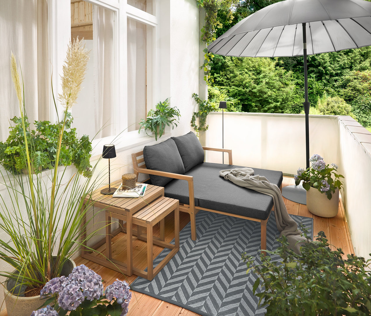 Zariadenie na balkóne s rozťahovacou záhradnou pohovkou, kobercom na použitie vonku (cca 165 x 115 cm), balkónovou clonou a ochranou proti vetru v krémovej farbe, čiernou LED akumulátorovou stolovou lampou do exteriéru a čiernou LED akumulátorovou stojacou lampou do exteriéru.