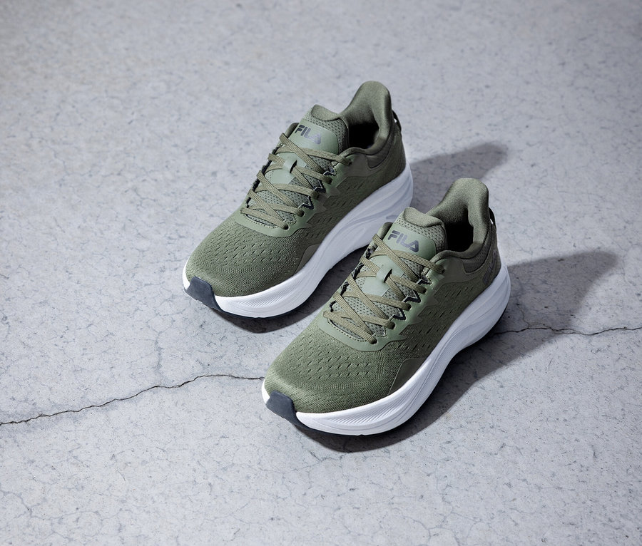 Dve olivovo zelené bežecké topánky Fila stoja na sivom pozadí.