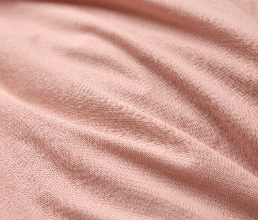 Detail záberu zvlnenej, svetloružovej látky.