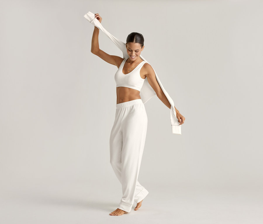 Žena v pyžamovej súprave a krémovej bezšvovej podprsenke drží vrchný diel.