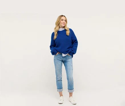 Žena má na sebe modrý pletený kabát a džínsy Angels Denim »Cira Boho«.