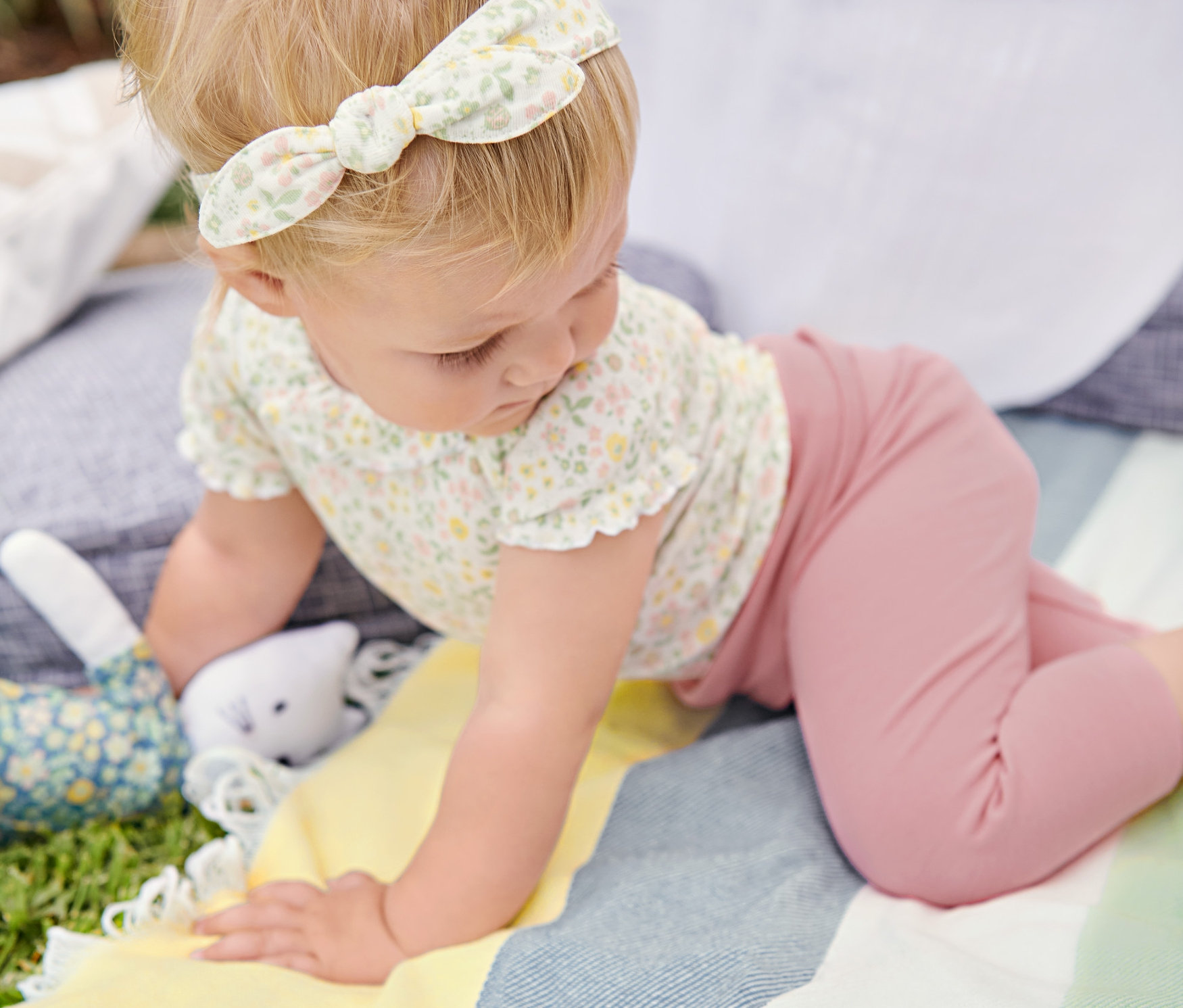 Dieťa lezie po XL deke na piknik. Má na sebe 3-dielnu súpravu pre bábätká.