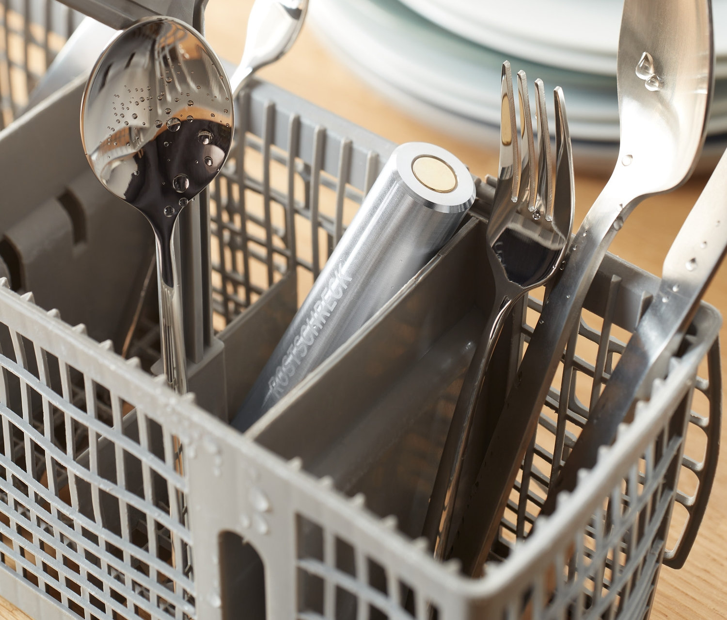 Strieborné príbory v sivom košíku v umývačke riadu s Odpudzovač hrdze do umývačky riadu.