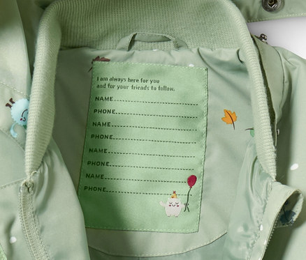 Vnútro zeleného overalu do dažďa s priestorom pre meno a telefónne číslo.