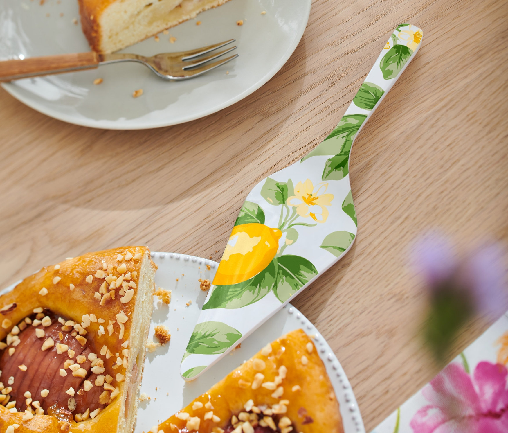 Kúsok torty s polevou a lyžicou krému leží na tanieri vedľa vidličky a lopatky na tortu.