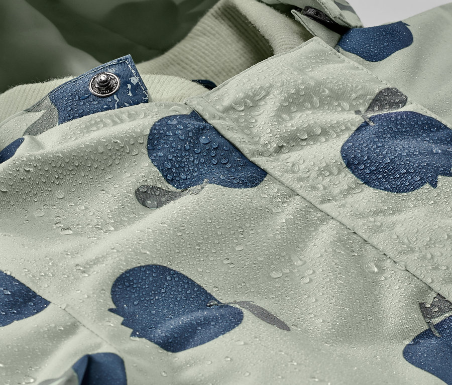 Detail detského overalu do dažďa s kvapkami vody a modrým vzorom.