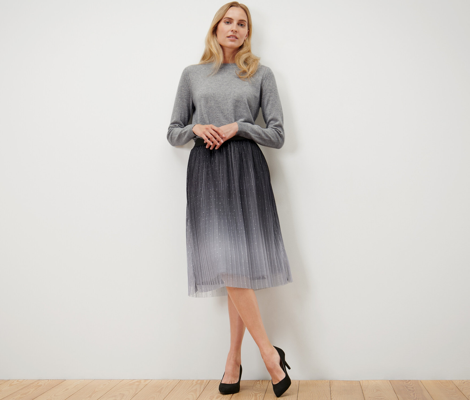 Žena pózuje v plisovanej tylovej sukni s farebným prechodom.