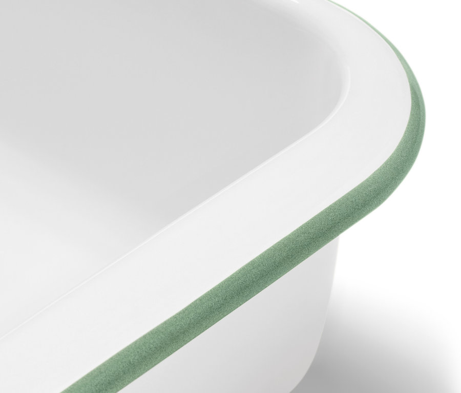 Detail bielej smaltovanej zapekacej misy s vekom a zeleným lemom.