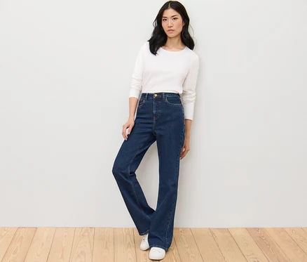 Žena pózuje v bootcut džínsoch – strih »Lou« a bielom tope.