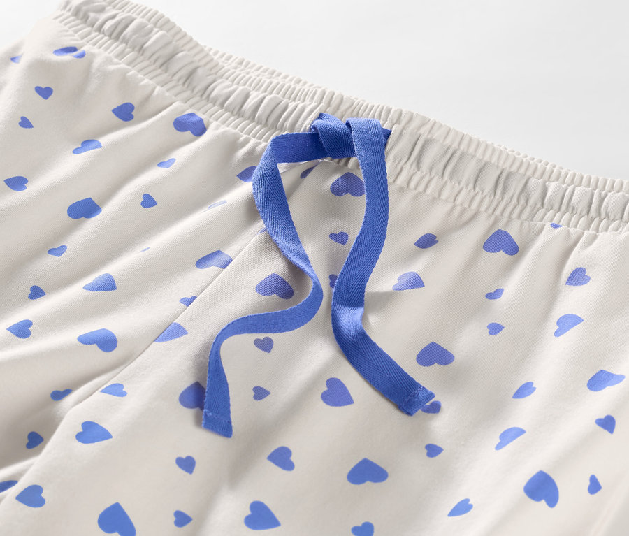 Detail pyžamových nohavíc so srdiečkami a modrou stuhou.