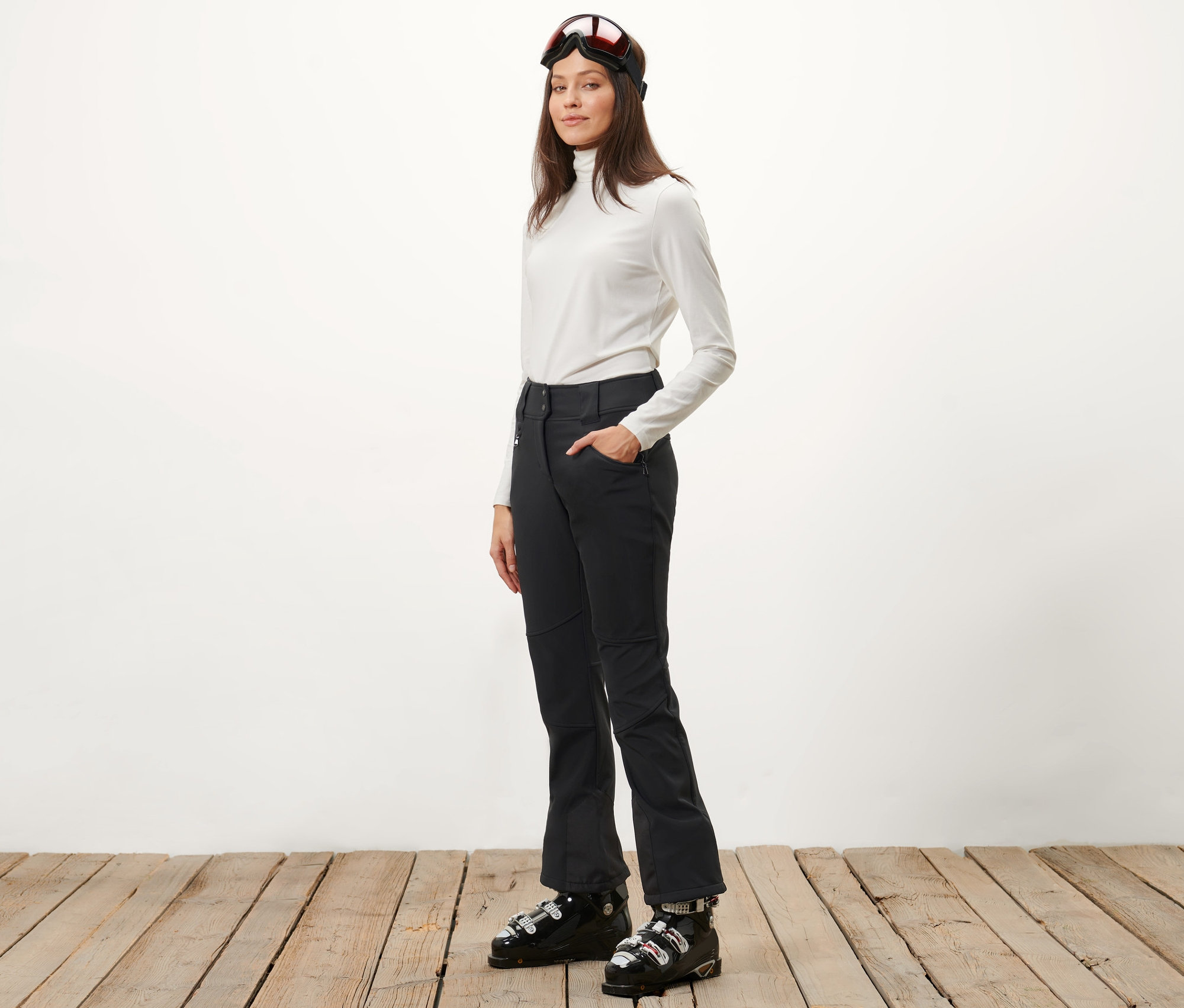 Žena pózuje v lyžiarskych nohaviciach Jet a lyžiarskych topánkach.