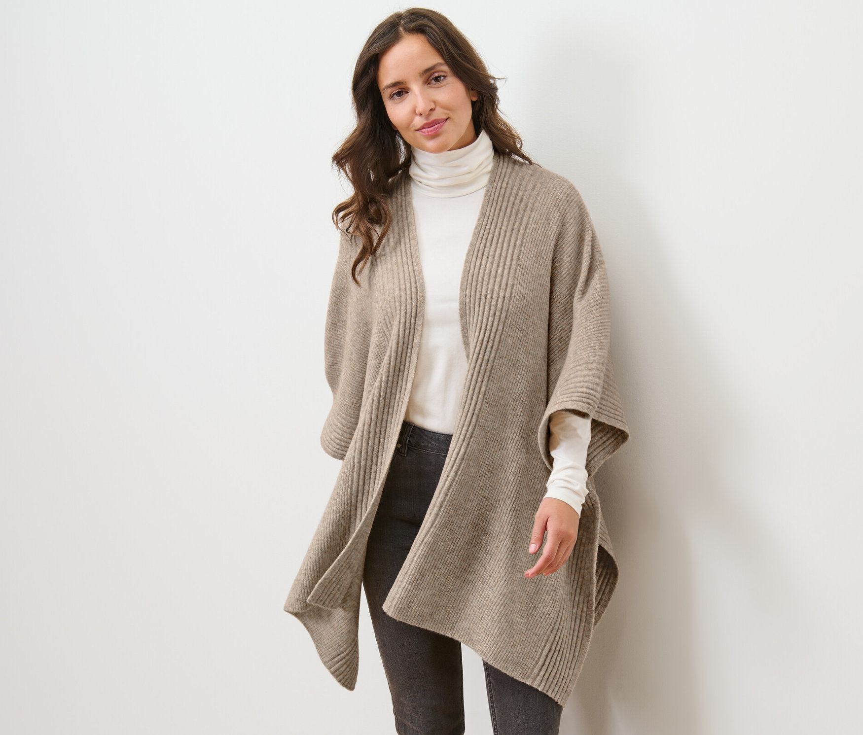 Žena má na sebe pletenú pelerínu.