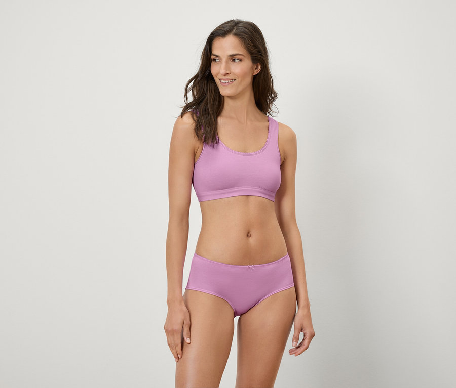 Žena pózuje v lila športovej podprsenke a boxerkách.