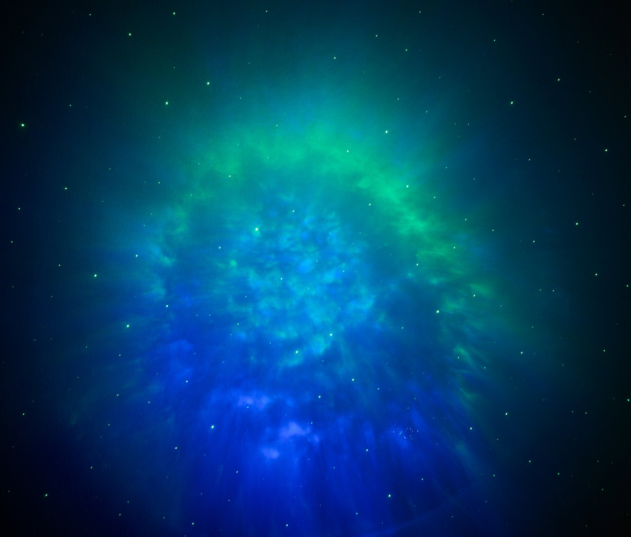 Rozmazaná fotografia hviezdokopy v odtieňoch modrej a zelenej farby.