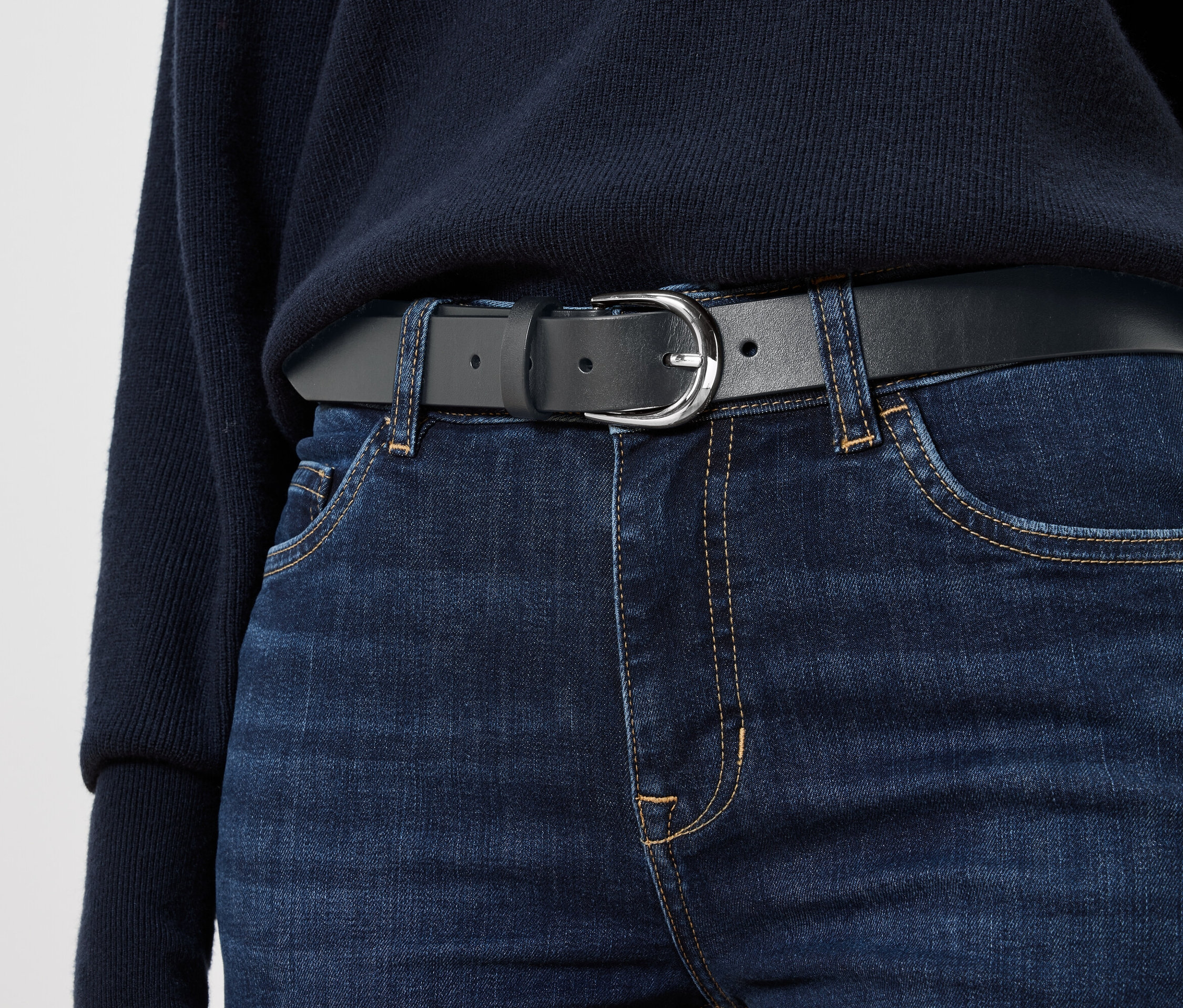 Čierny kožený opasok na modrých džínsoch.