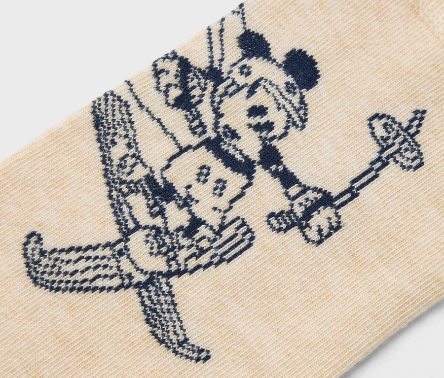 Detail béžovej ponožky s tmavomodrým vzorom Mickeyho Mousa na lyžiach.