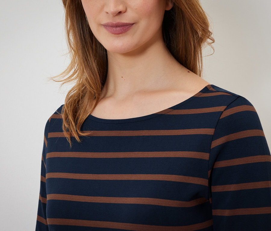 Horná časť tela ženy v pruhovanom tričku s dlhým rukávom.