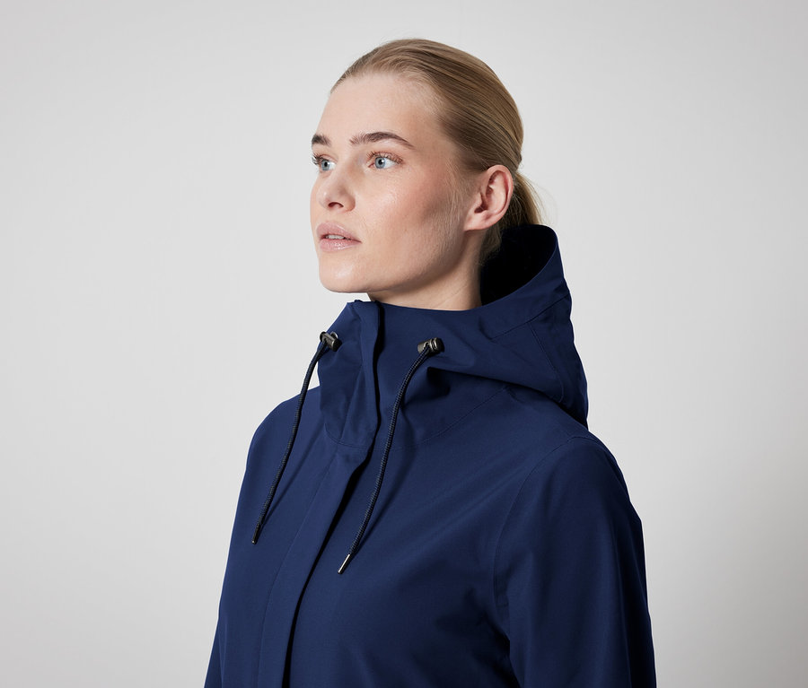 Žena má na sebe tmavomodrú bundu s kapucňou.