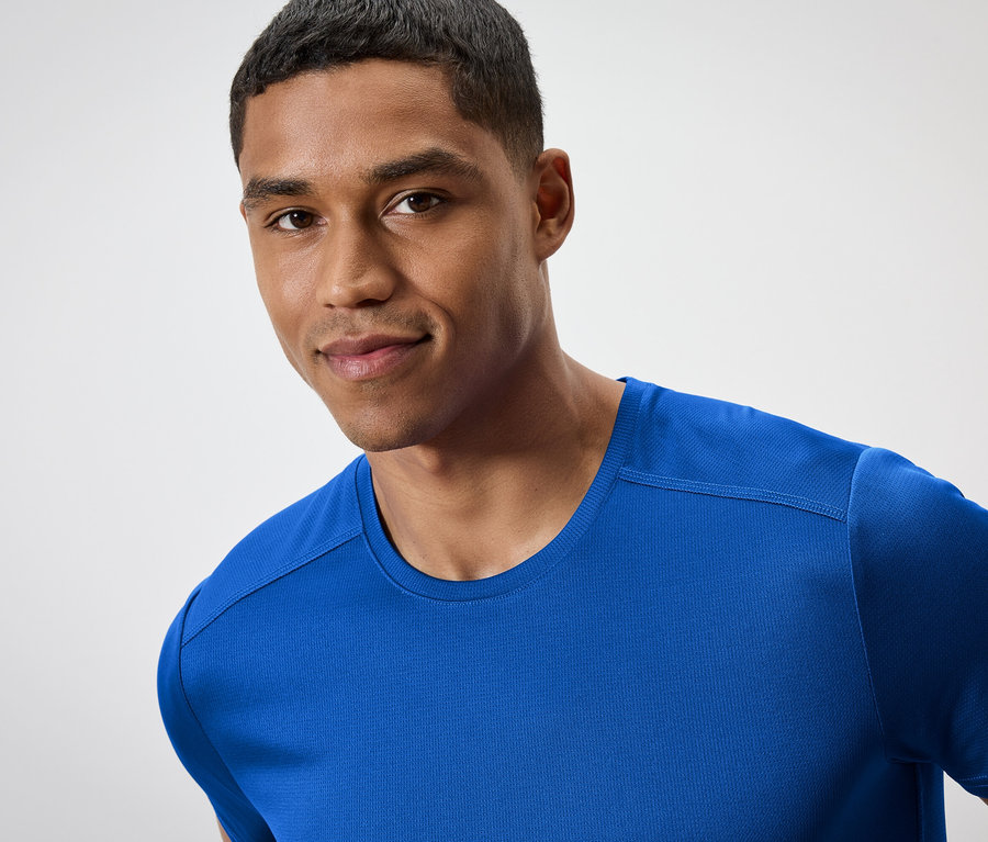 Portrét usmievajúceho sa muža v modrom tričku.