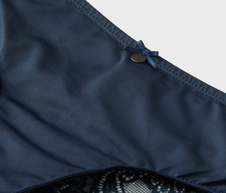 Detailný záber na tmavomodré nohavičky s čipkou a mašľou.