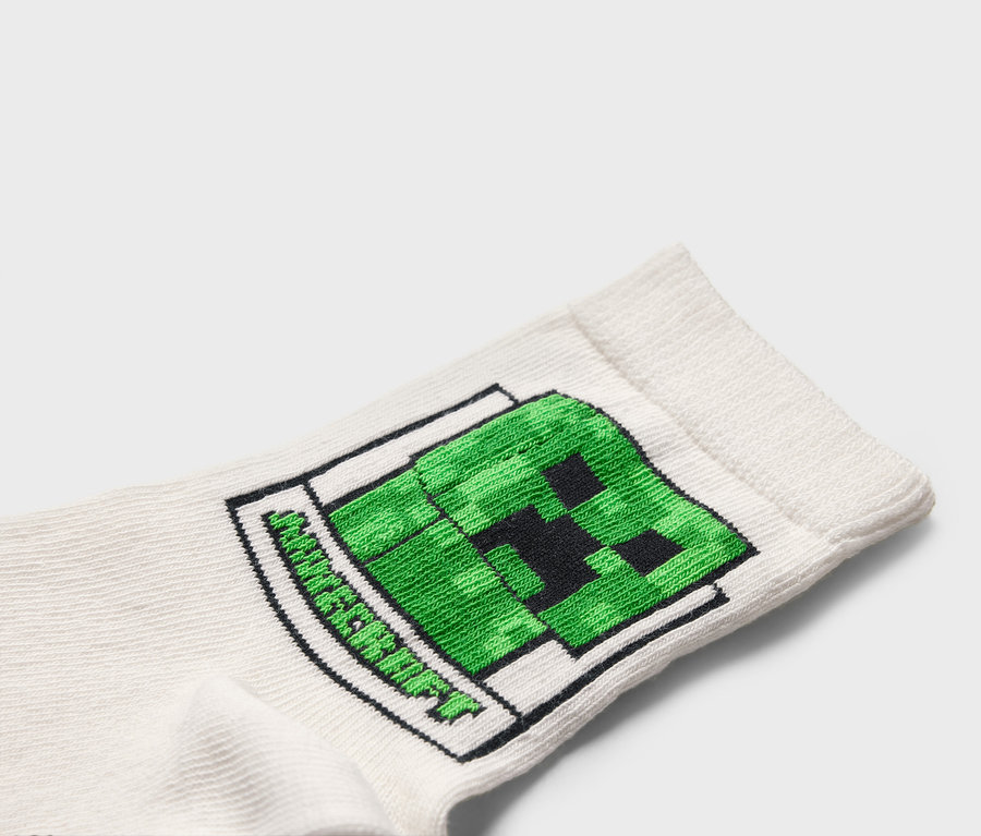 Detail bielej ponožky so zeleným motívom Minecraft Creeper.
