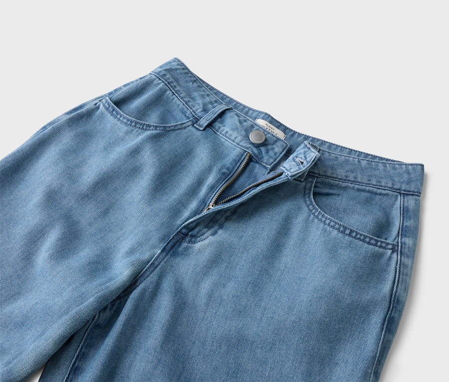 Detailný záber svetlomodrých džínsov s otvoreným zipsom.
