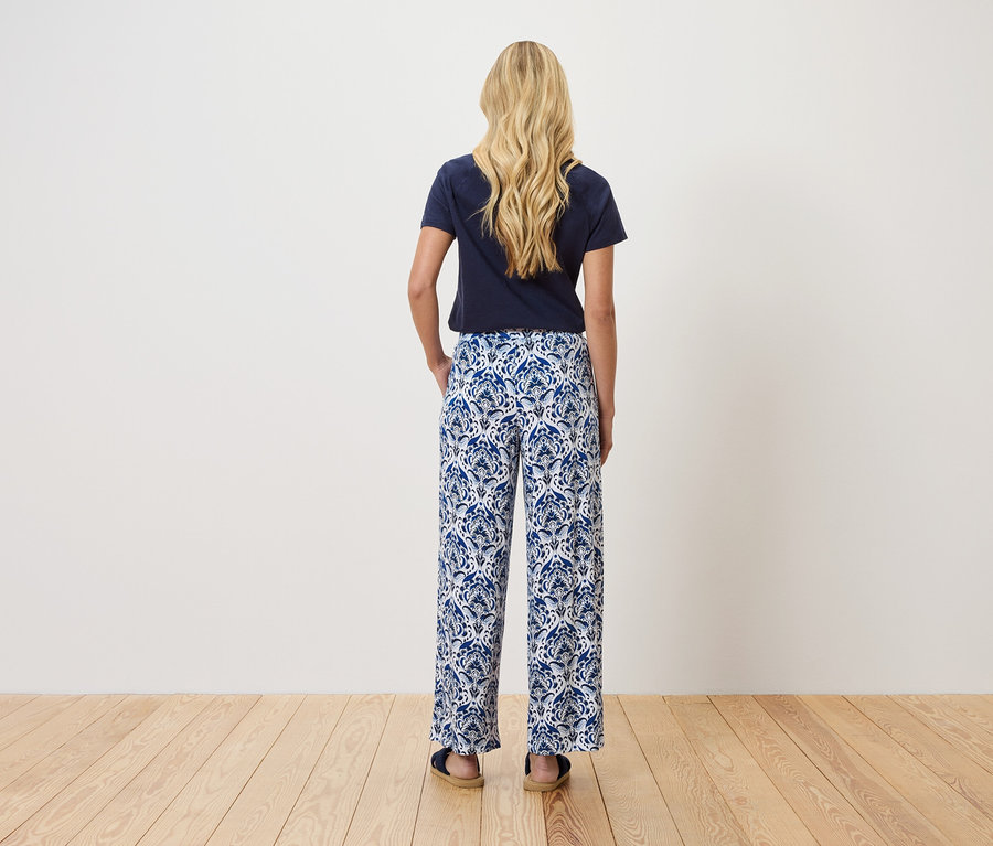 Pohľad zozadu na blondínku v tmavomodrom tričku a modro-biele vzorované nohavice.