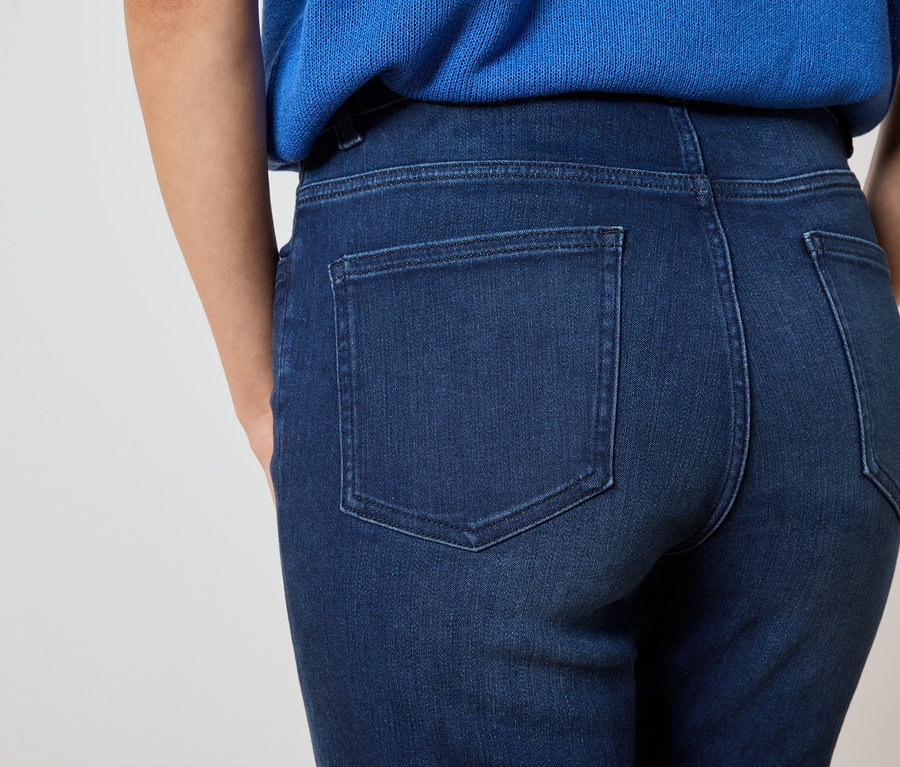 Detailný záber na zadnú časť ženy v tmavomodrých džínsoch a modrej blúzke.