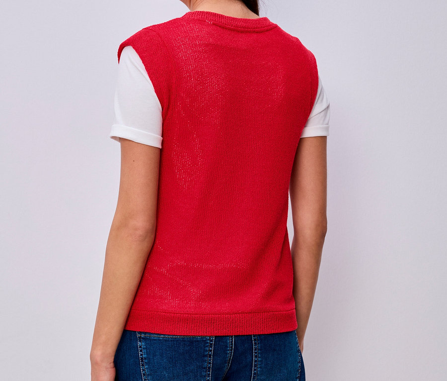 Žena zozadu v tričku Street One, červenej pletenej veste, modrých džínsoch a bielom tričku.