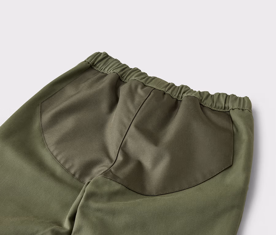 Detailný záber na zadnú časť zelených nohavíc s elastickým pásom a našitými vreckami.