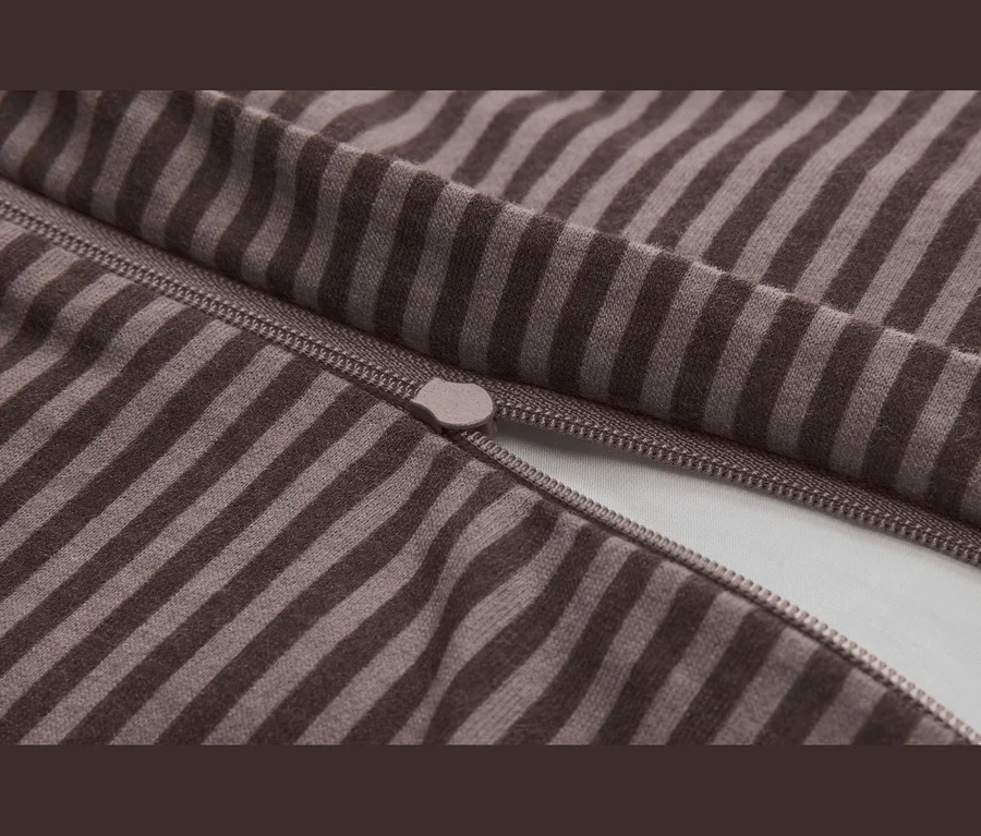Detail hnedo-béžovej pruhovanej látky s čiastočne otvoreným zipsom a viditeľným jazdcom.